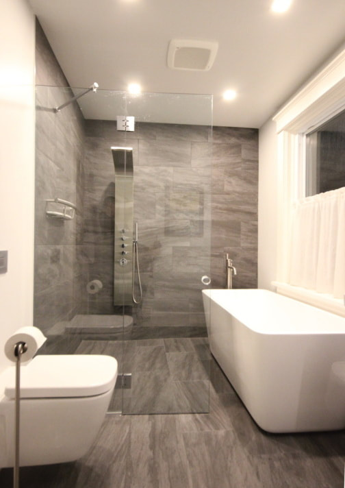 Custom bathroom with curbless, linear drain shower, freestanding bathtub and Cube wall hung toilet in Almonte by Renovation to Perfection