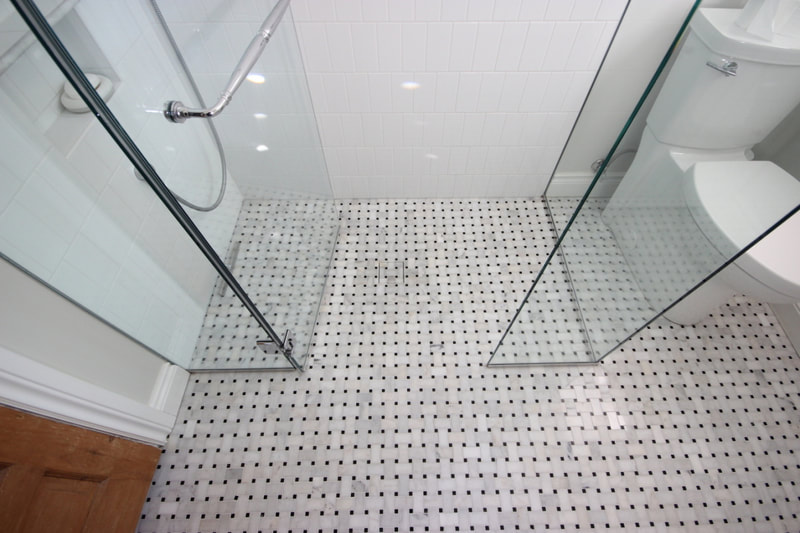 Custom curbless shower with subway tiles on the walls and basketweave mosaic on the floor with Schluter tileable grate in Renfrew by Renovation to Perfection.