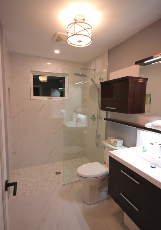 Small bathroom with curbless walk-in shower with the window and wall hung cabinetry in Almonte by Renovation to Perfection.