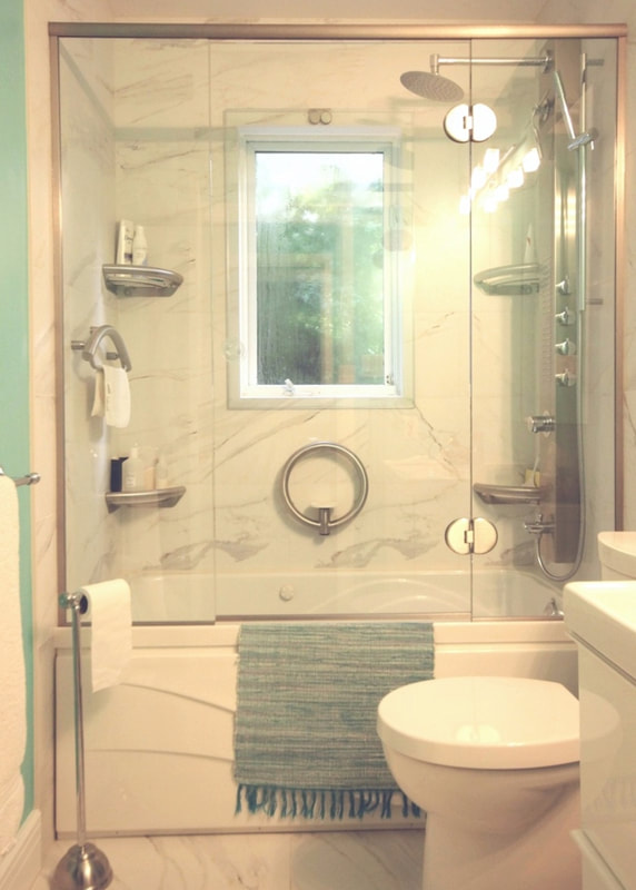 Whirlpool bathtub with tiled surround, custom glass enclosure and Invisia corner shelves, towel bar and soap dish grab bars in Clayton by Renovation to Perfection.