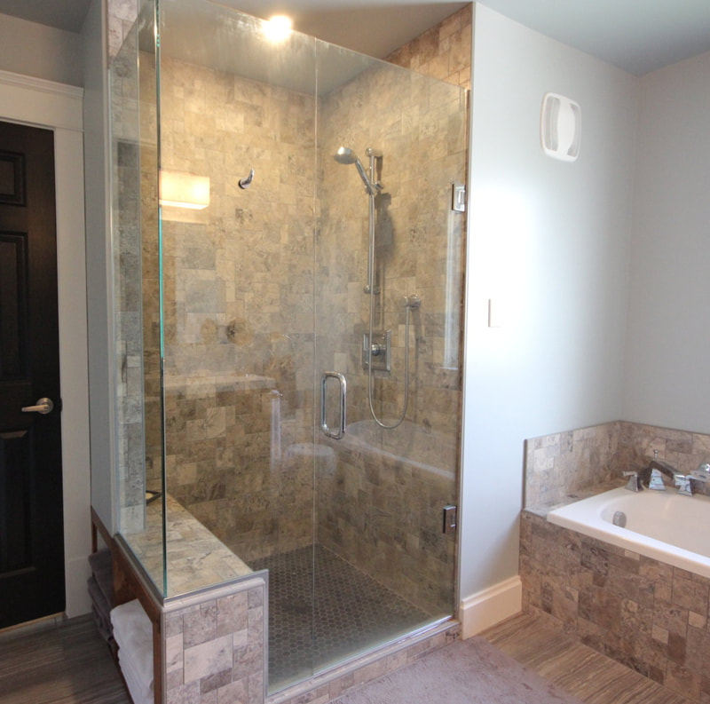 Bathroom with custom stone mosaic shower with towel storage shelf under the build in shower bench in Ottawa by Renovation to Perfection.