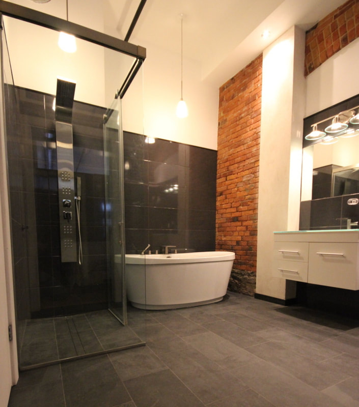 Custom bathroom in the heritage Thoburn Mill in Almonte featuring freestanding bathtub, curbless, linear drain shower, wall hung vanity with glass countertop and heated slate tile floor  by Renovation to Perfection.