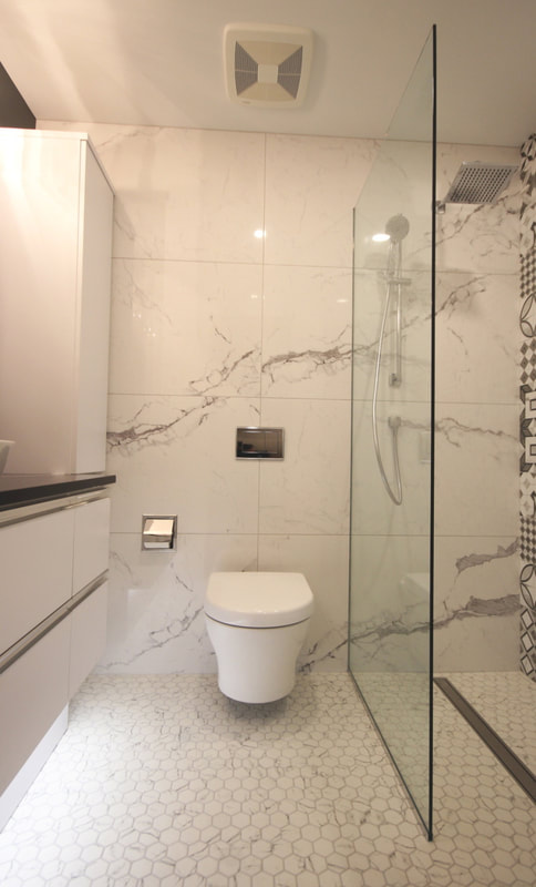 Wall hung toilet on the large tiles wall, glass mosaic on the floor with the curbless, linear drain shower. LED undercabinet light integrated into the vanity cabinet in Ottawa by Renovation to Perfection.